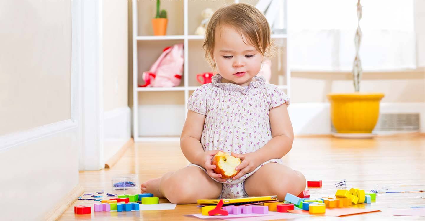Kleinkind sitzt auf dem Boden mit Spielzeug