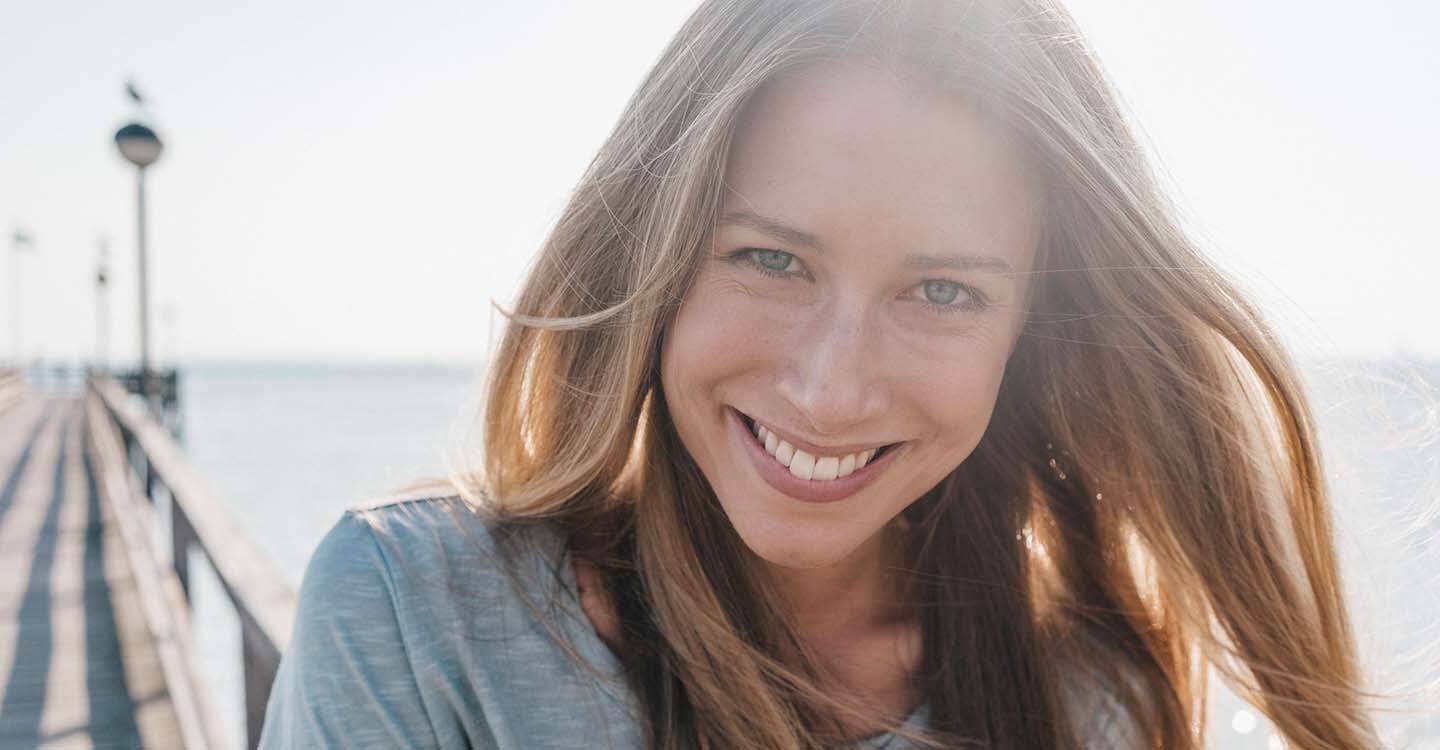 Lächelnde Frau auf einem Steg am Meer