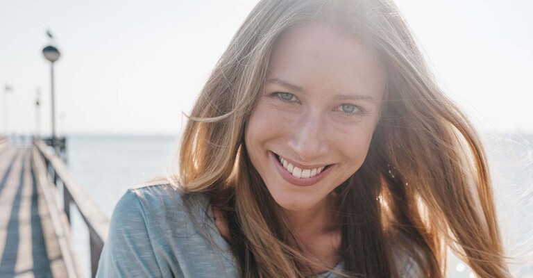Lächelnde Frau auf einem Steg am Meer