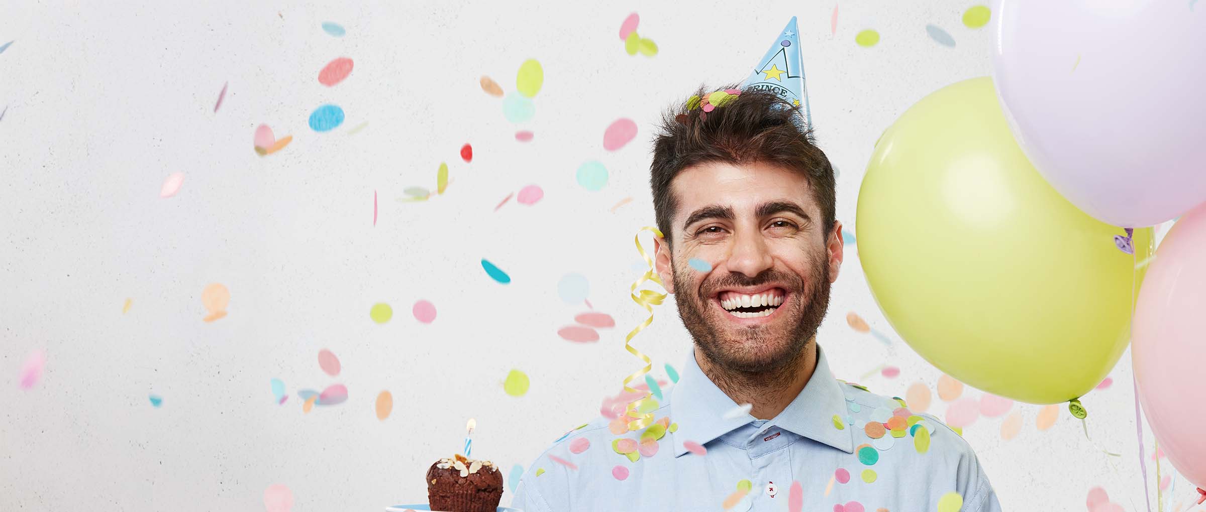Mann mit Ballons und einem Cupcake in der Hand