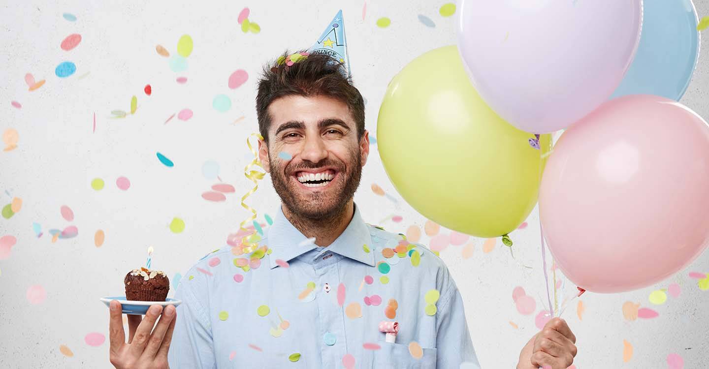 Mann mit Ballons und einem Cupcake in der Hand