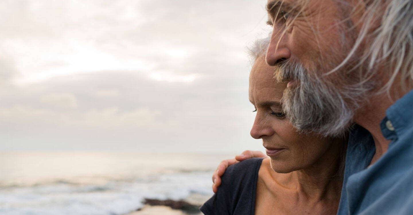 Mann und Frau stehen am Meer und schauen in die Ferne