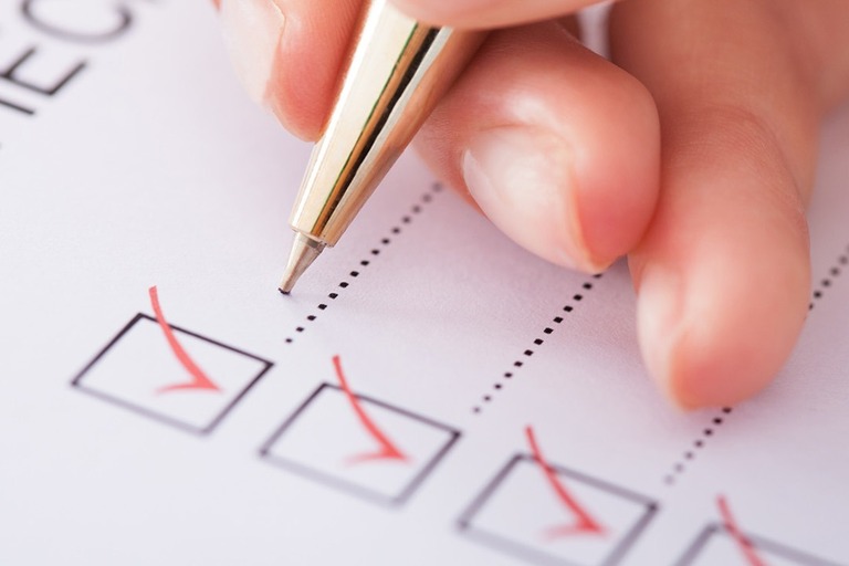 Nahaufnahme Hand mit Kugelschreiber und einer Checkliste