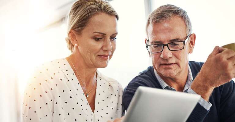 Eine Frau die zusammen mit einem Mann in ein Tablet schauen