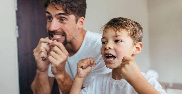 Vater und Sohn benutzen Zahnseide