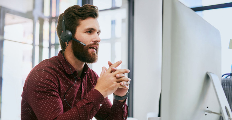 Ein Servicemitarbeiter mit Headset am Computer
