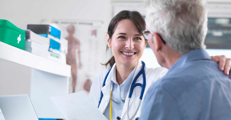Ärztin lächelt ihren Patienten an und legt ihm die Hand auf die Schulter