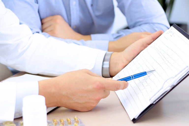 Ein Mann zeigt mit einem Stift auf eine Liste die in der Hand hält