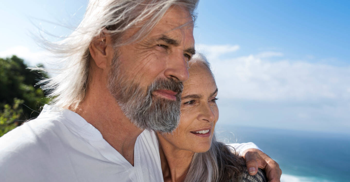 Mann legt Frau Arm um die Schulter und schaut in die Ferne 