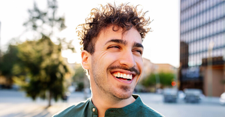 Junger Mann mit Locken lacht 