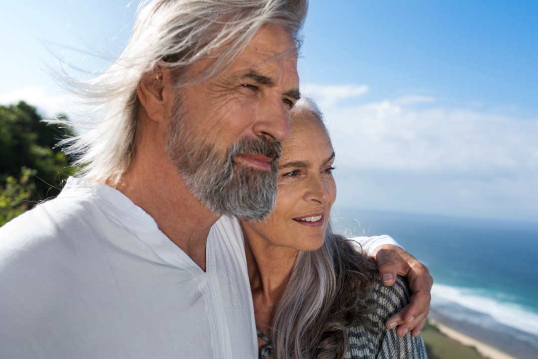 Mann legt Frau Arm um die Schulter und schaut in die Ferne 