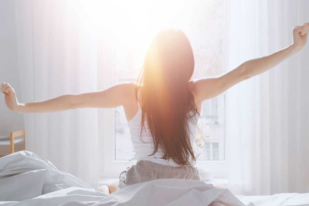 Eine Eine Frau mit ausgestreckten Armen auf einem Bett von hinten fotografiert